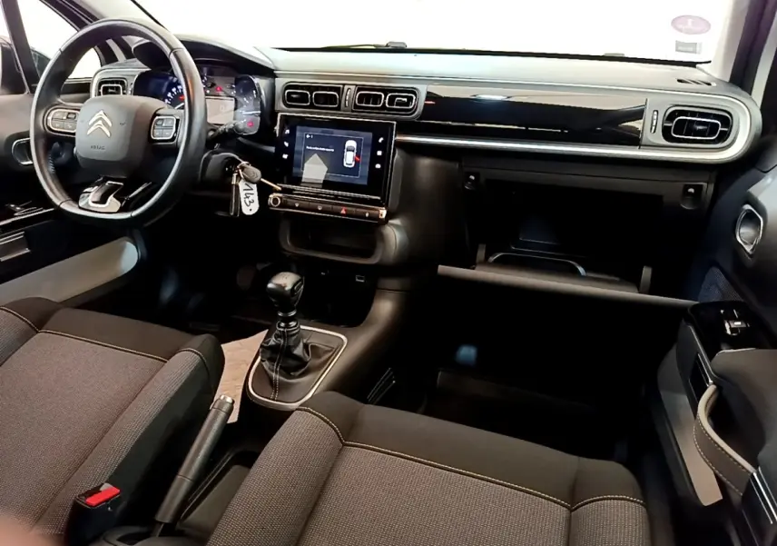 Vue intérieure avant de la Citroën C3 blanche 2021, tableau de bord noir avec écran tactile et volant cuir multifonctions.