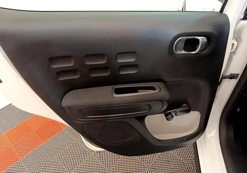 Vue intérieure de la porte arrière gauche blanche d'une Citroën C3 2021 avec poignée manuelle et haut-parleur intégré.