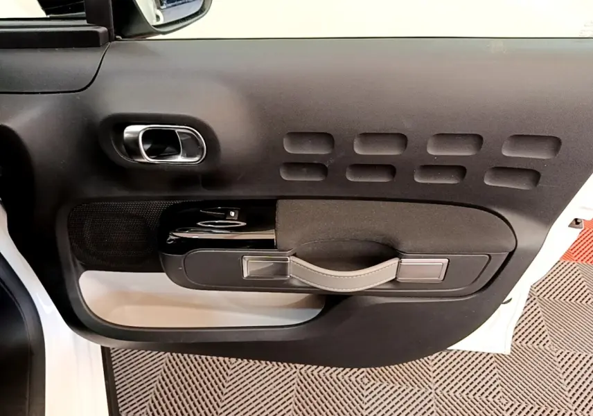Vue intérieure de la porte avant gauche blanche d'une Citroën C3 2021 avec poignée noire et détails argentés.