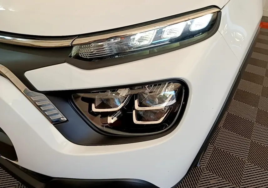 Gros plan sur le phare avant droit blanc d'une Citroën C3 2021 avec feux LED et détails chromés.
