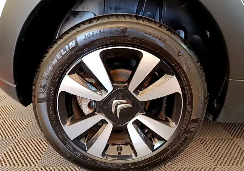 Gros plan sur la roue avant droite d'une Citroën C3 blanche, mettant en valeur la jante alliage bicolore et le pneu Michelin.