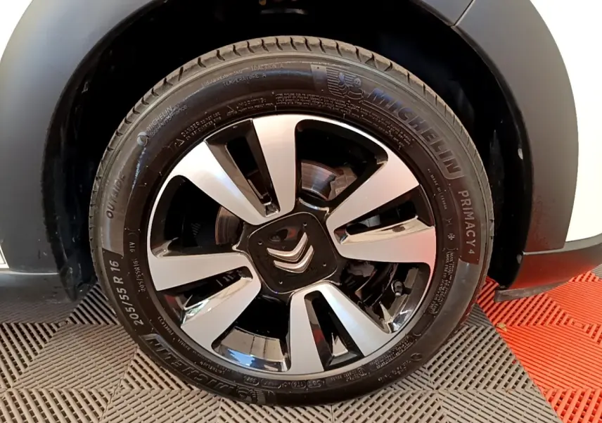 Gros plan sur la roue avant droite d'une Citroën C3 blanche, jante alliage bicolore avec logo Citroën central.