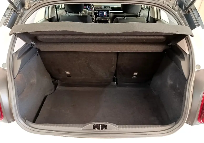 Coffre ouvert vu de l'arrière d'une Citroën C3 blanche, montrant l'espace de chargement et l'intérieur noir.