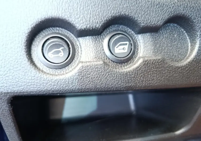 Gros plan sur les boutons d’ouverture du coffre et de la trappe à carburant dans l’habitacle de l’AIXAM AMBITION 0.5 CITY SPORT bleu.