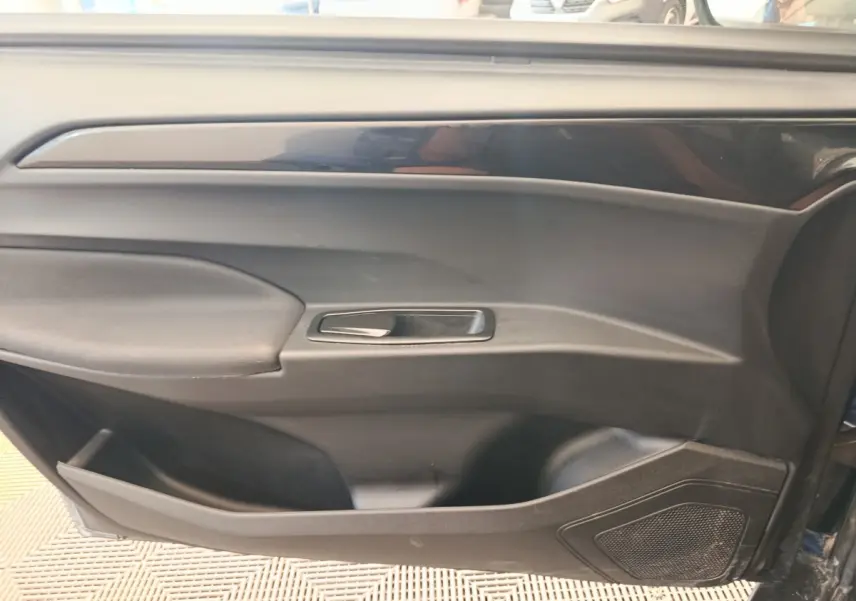 Vue rapprochée de la porte côté conducteur de l'AIXAM AMBITION 0.5 CITY SPORT 2024 en bleu, avec poignée et haut-parleur intégrés.
