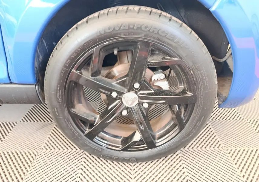 Gros plan sur la roue avant droite noire d’une Aixam Ambition 0.5 City Sport bleu 2024.