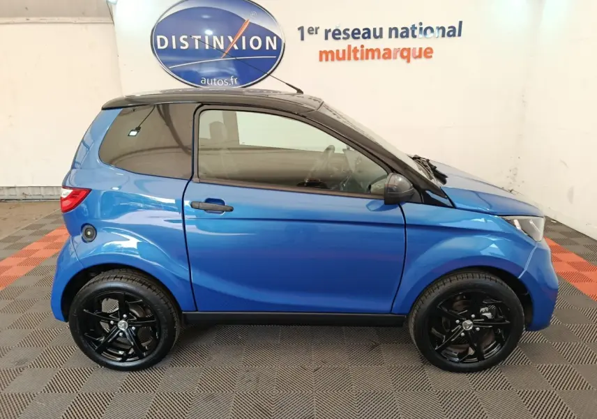 Vue de profil côté gauche d'une Aixam Ambition 0.5 City Sport 2024 bleu avec jantes noires et rétroviseur conducteur.