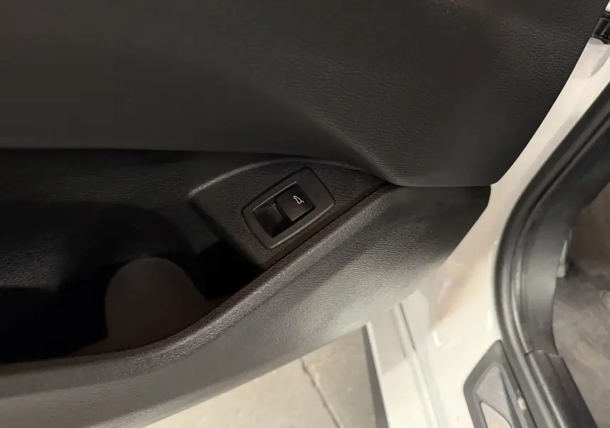Gros plan sur le bouton d'ouverture électrique du hayon, sur la porte côté gauche d'un BMW X2 blanc.