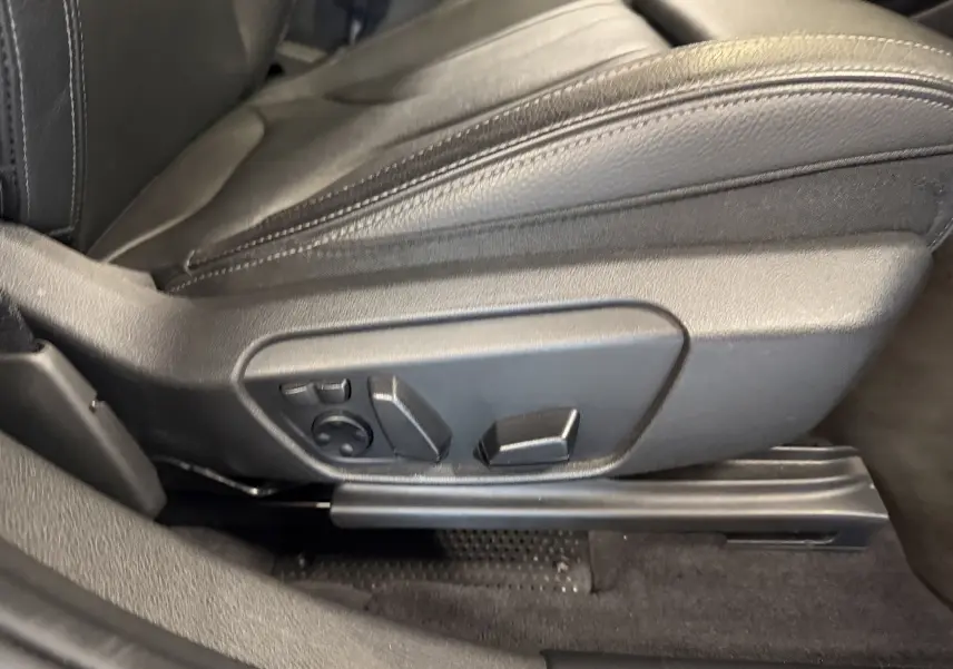 Détail du siège conducteur noir avec commandes électriques de réglage sur BMW X2 sDrive18d 2023.