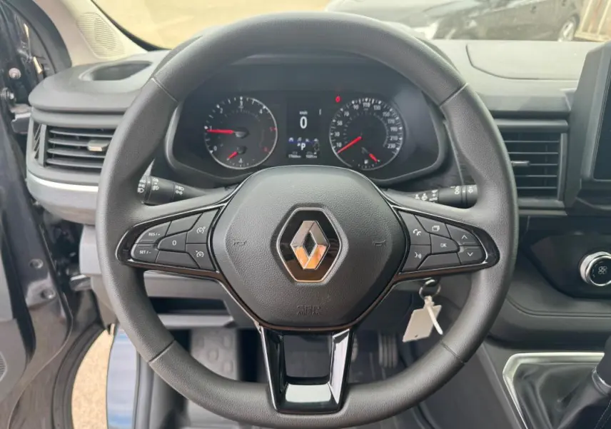Vue intérieure centrée sur le volant noir du Renault Trafic Fourgon 2024 avec tableau de bord et commandes visibles.