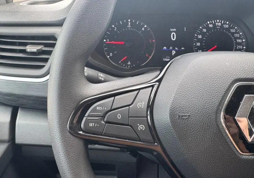 Vue rapprochée du volant Renault Trafic Fourgon 2024 avec commandes de régulateur de vitesse et tableau de bord numérique.