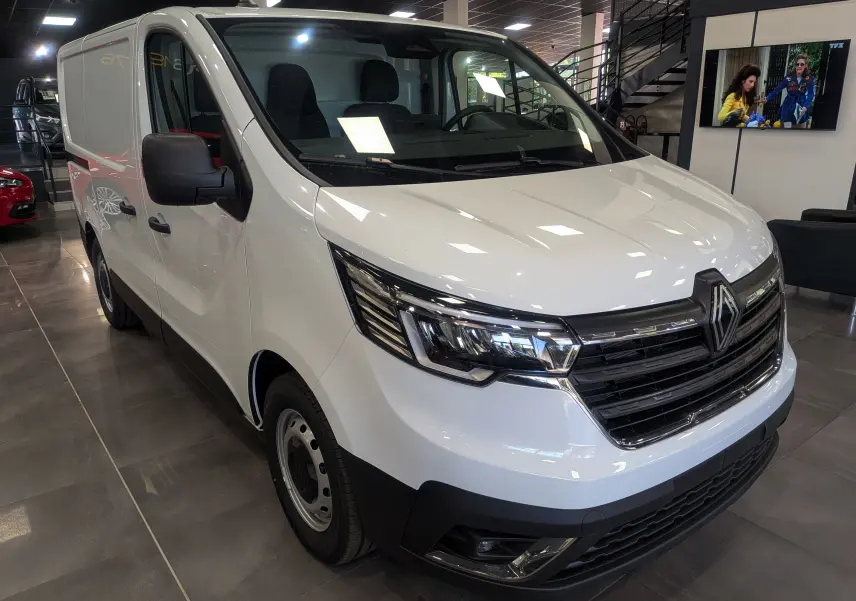 Renault Trafic Fourgon blanc glacier vu en 3/4 avant droit dans un showroom avec calandre noire distinctive.