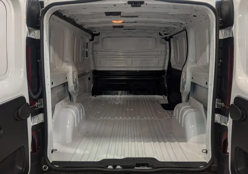 Vue arrière intérieure du Renault Trafic Fourgon blanc glacier L1H1 3T, montrant l'espace de chargement vide et la structure métallique.