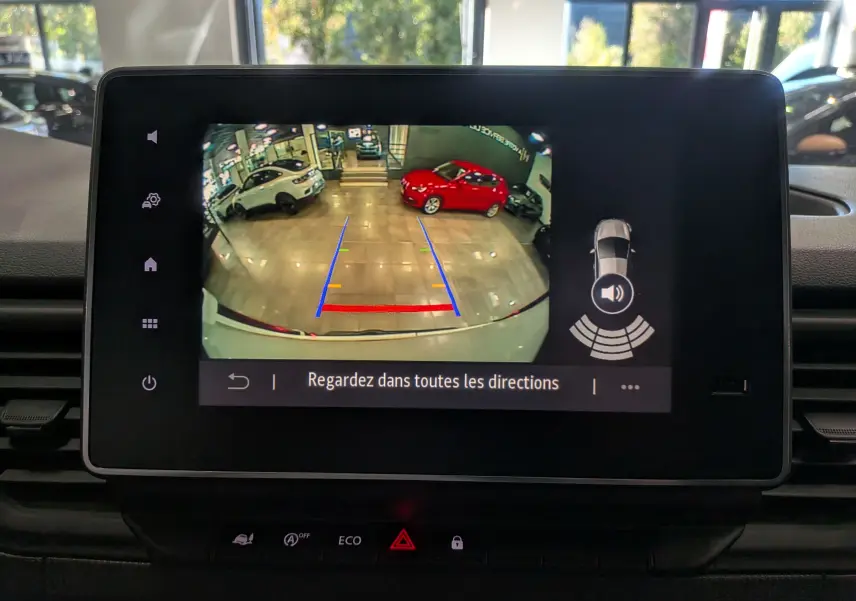 Écran multimédia montrant la caméra de recul du Renault Trafic Fourgon blanc glacier, avec lignes de guidage colorées.