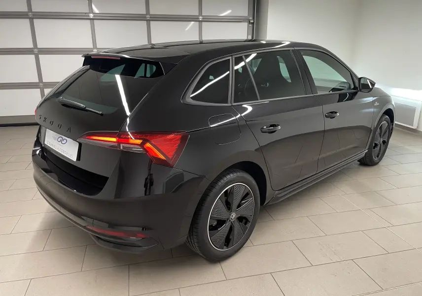 Vue 3/4 arrière droite d'une Skoda Scala 2025 Noir Magic avec feux arrière allumés et jantes spécifiques Monte-Carlo.