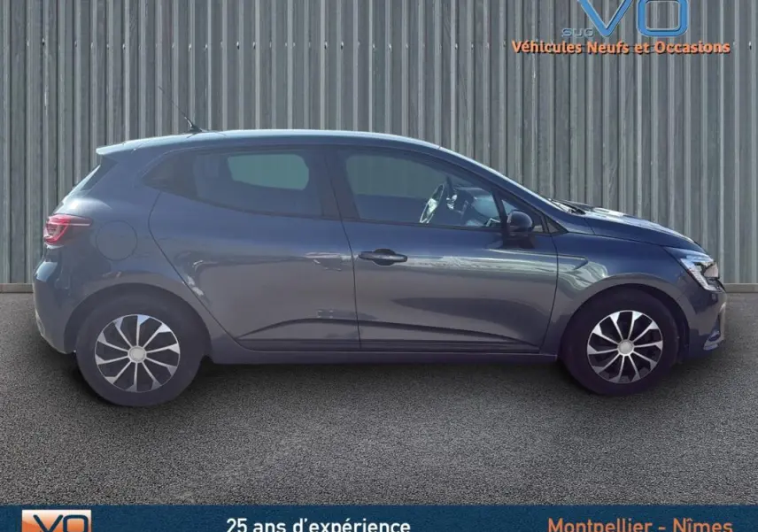 Profil côté gauche d'une Renault Clio gris 2022 V TCe 90 Equilibre garée devant un mur métallique.
