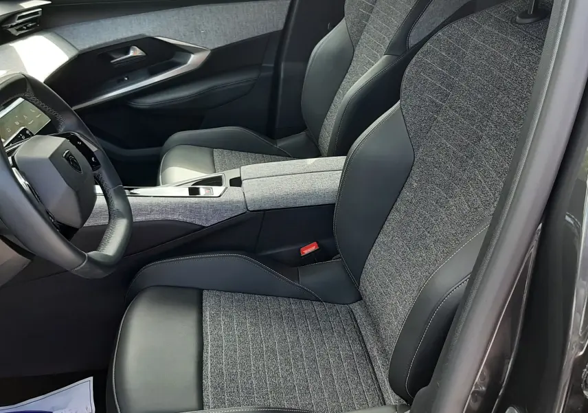 Vue intérieure côté conducteur du Peugeot 5008 Hybrid 145ch Allure 2025, sièges tissu gris et cuir noir, détails modernes.