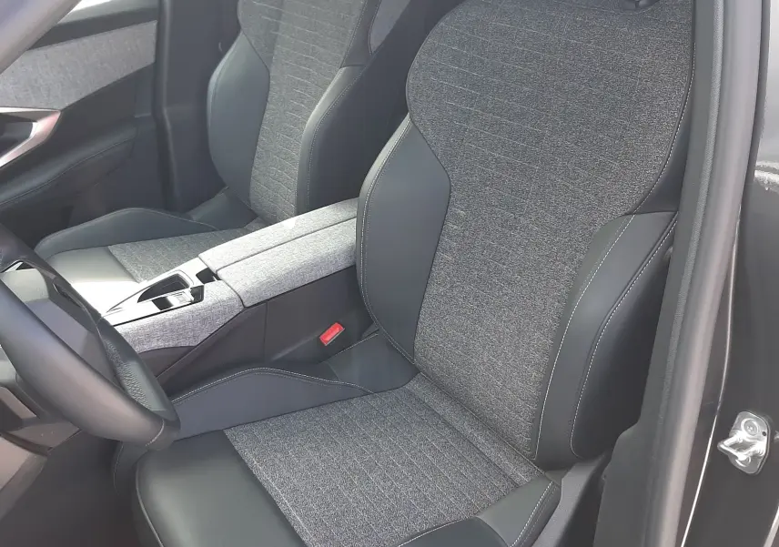 Vue intérieure côté conducteur du Peugeot 5008 Hybrid 145ch Allure 2025, sièges tissu gris et cuir noir, console centrale assortie.