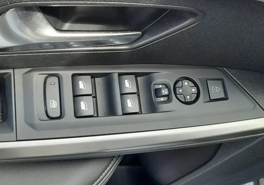 Vue rapprochée des commandes de porte côté gauche du Peugeot 5008 Hybrid gris titane, avec boutons de vitres et rétroviseurs.