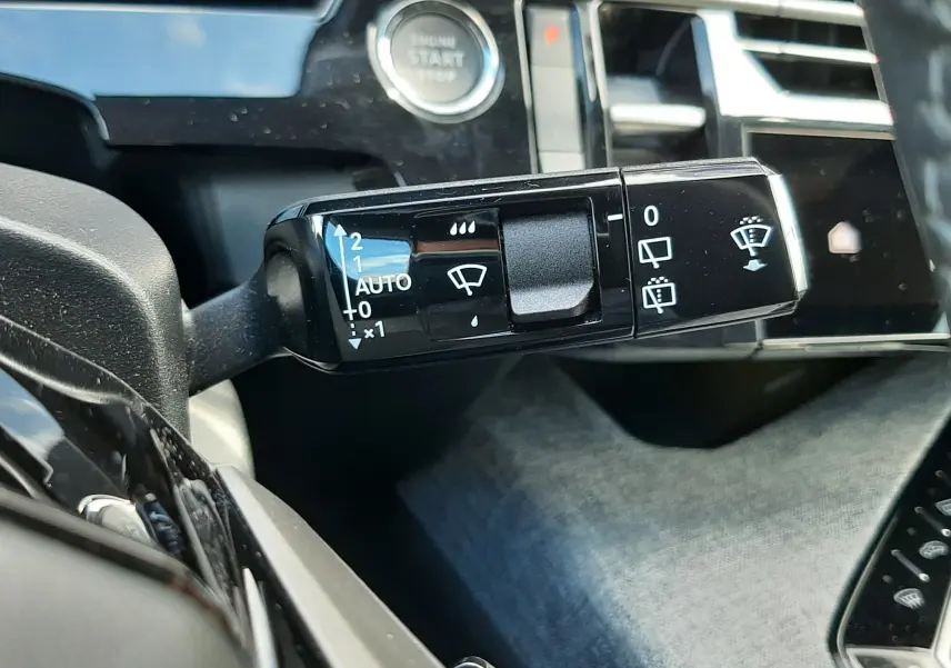 Gros plan sur la commande des essuie-glaces à droite du volant dans l’habitacle gris noir du Peugeot 5008 Hybrid 2025.