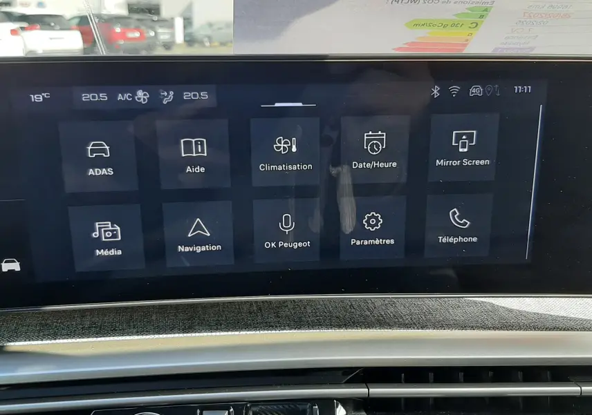 Vue rapprochée de l’écran tactile central et de la console de la Peugeot 5008 Hybrid 145ch Allure gris titane, affichant les menus climatisation et navigation.