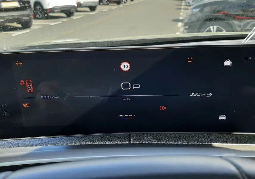 Tableau de bord numérique du Peugeot 5008 Hybrid 2025 vu de face, affichant l'autonomie et les alertes.