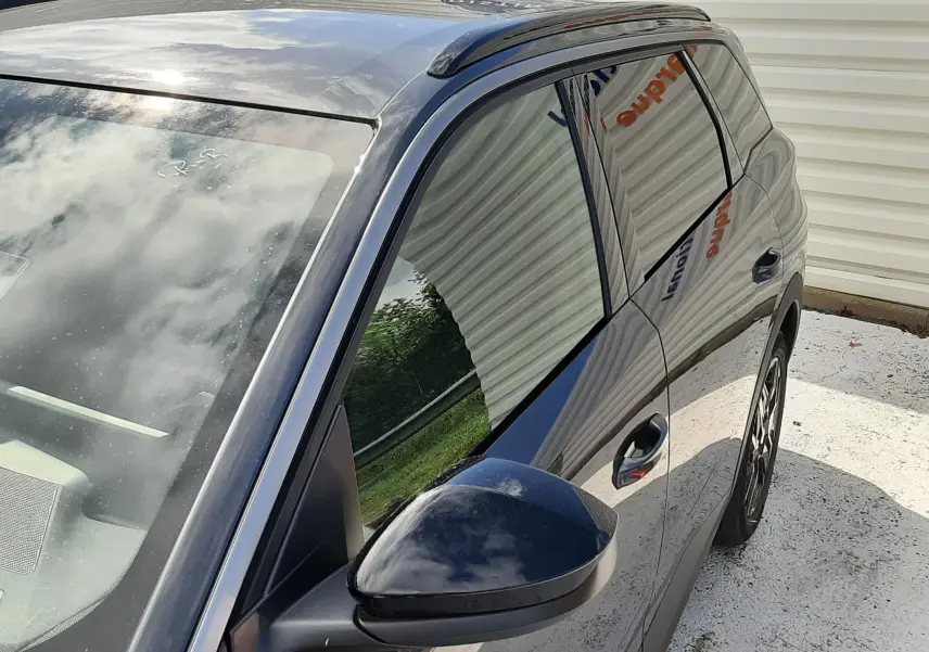 Vue 3/4 avant droit du Peugeot 5008 Hybrid gris titane métal, mettant en valeur la surface lisse et le rétroviseur noir.