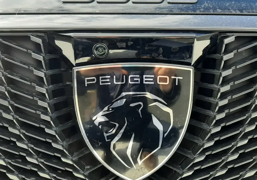 Gros plan sur la calandre noire et le logo lion argenté du Peugeot 5008 gris titane, mettant en valeur l’inscription 5008.