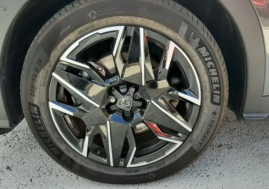 Gros plan sur la roue avant droite du Peugeot 5008 Hybrid gris titane, avec jante alliage noire et argentée et pneu Michelin.