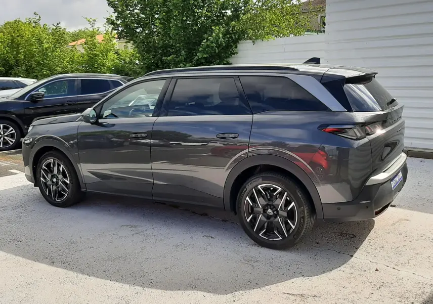 Peugeot 5008 Hybrid gris titane métal vue de profil côté gauche, avec jantes alliage noires et toit panoramique.