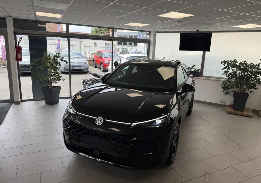 Volkswagen T-Roc R-Line eTSI 150Ch noir intense vu de 3/4 avant droit en showroom avec éclairage intérieur.