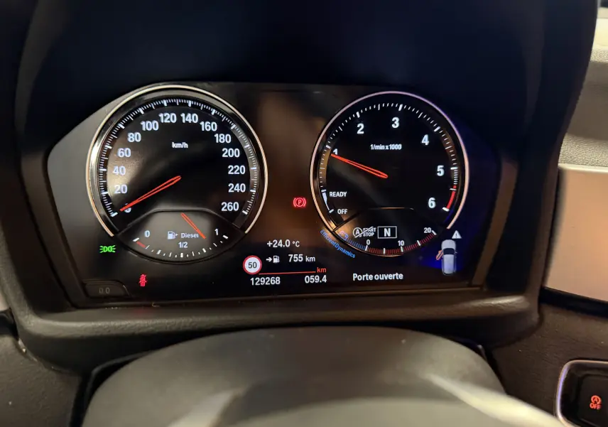Vue rapprochée du tableau de bord du BMW X1 noir 2019, affichant compteurs et indicateurs numériques.
