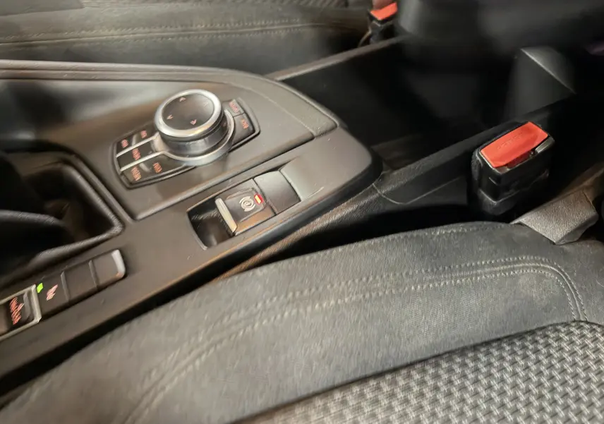 Détail de la console centrale noire du BMW X1 F48 2019, avec molette de contrôle et frein à main électronique.