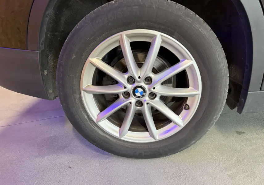 Gros plan sur la roue avant droite d’un BMW X1 noir 2019, mettant en valeur la jante alliage à dix branches.