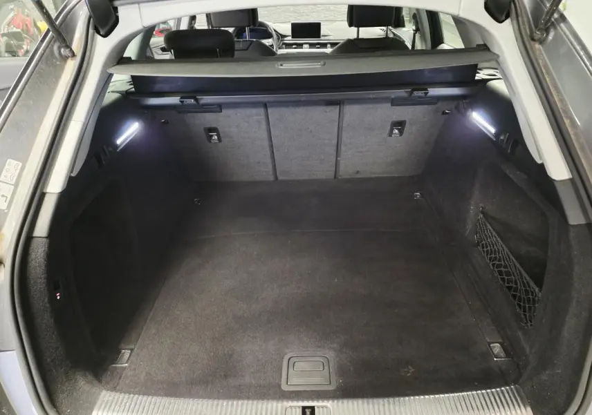 Coffre spacieux ouvert de l'Audi A4 Avant gris 2018, avec éclairage intérieur et filet de rangement latéral.