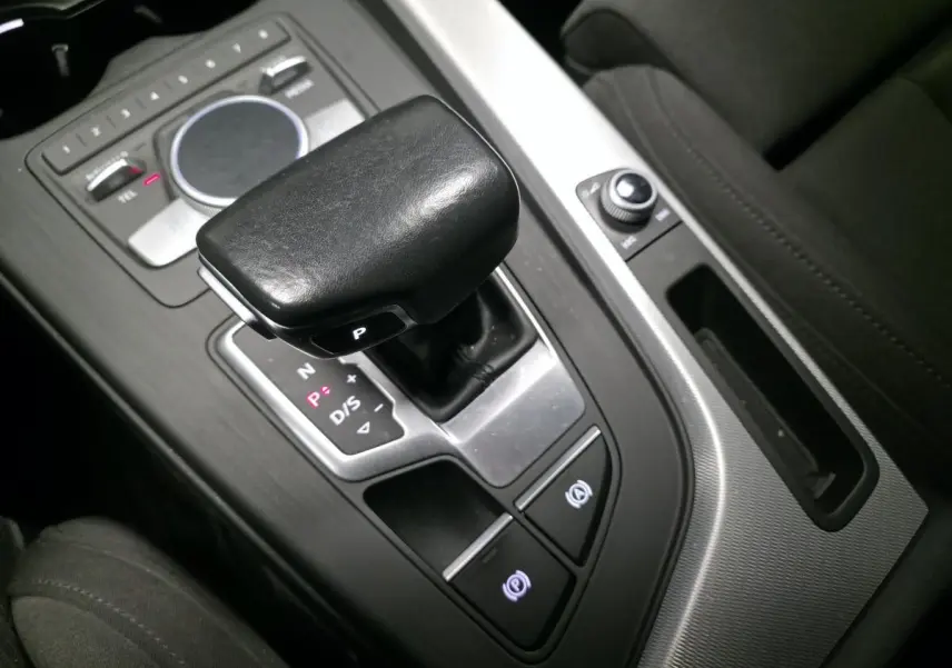 Gros plan sur le levier de vitesses automatique noir et la console centrale aluminium d'une Audi A4 Avant gris, intérieur tissu noir.