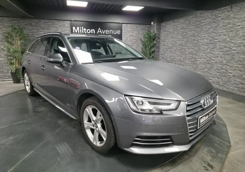 Audi A4 Avant gris métallisé vue 3/4 avant droit avec jantes alu 17 pouces dans un showroom intérieur.
