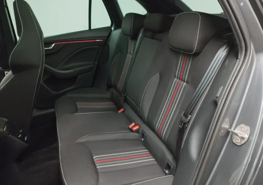 Vue intérieure arrière droite des sièges arrière noirs avec surpiqûres blanches et bandes rouges d'une Skoda Scala 2025 Gris Graphite.