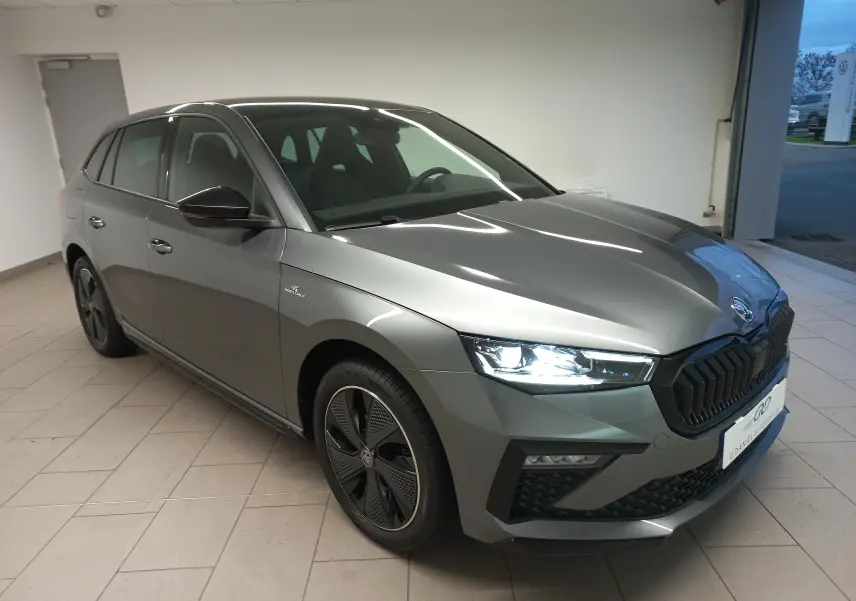Vue 3/4 avant droite d'une Skoda Scala 2025 gris graphite avec phares allumés et jantes spécifiques Monte-Carlo.