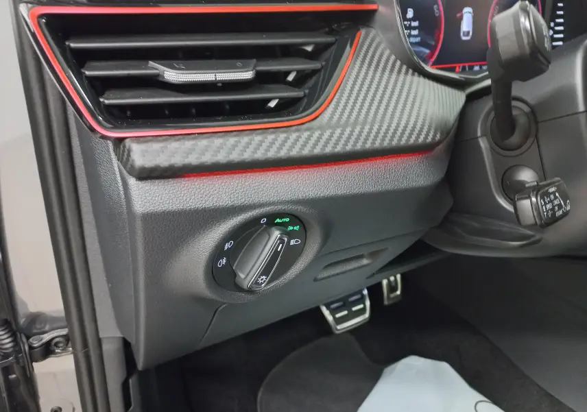 Détail du tableau de bord côté gauche d'une Skoda Scala Monte-Carlo avec éclairage automatique et insert carbone rouge.