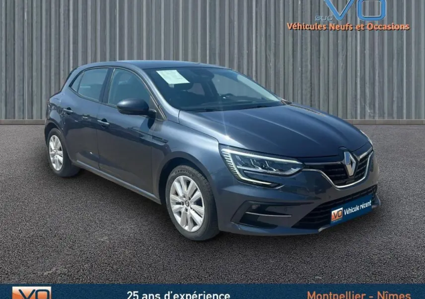 Renault Mégane IV Berline gris vue 3/4 avant droit, avec phares LED et jantes 16 pouces sur parking.