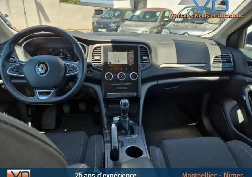 Intérieur de la Renault Mégane IV Business 2020, vue de face sur le tableau de bord gris avec écran tactile et boîte manuelle.