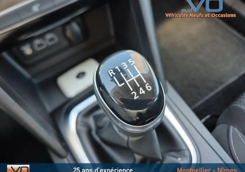 Gros plan sur le levier de vitesses manuel noir de la Renault Mégane IV Business gris, intérieur avec console centrale visible.