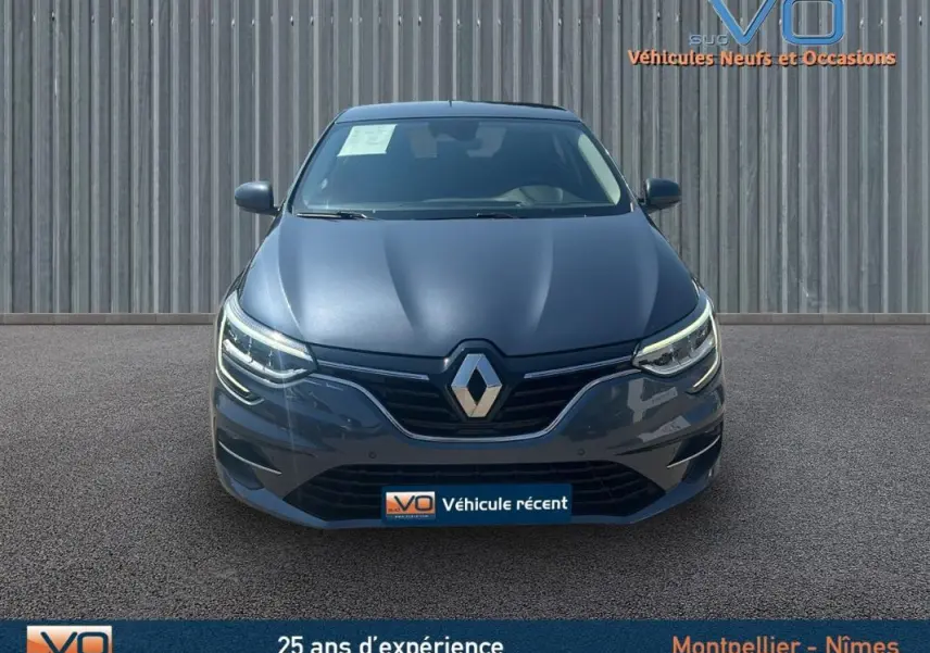 Vue avant d'une Renault Mégane IV Berline gris métallisé, mettant en valeur ses phares LED et calandre distinctive.