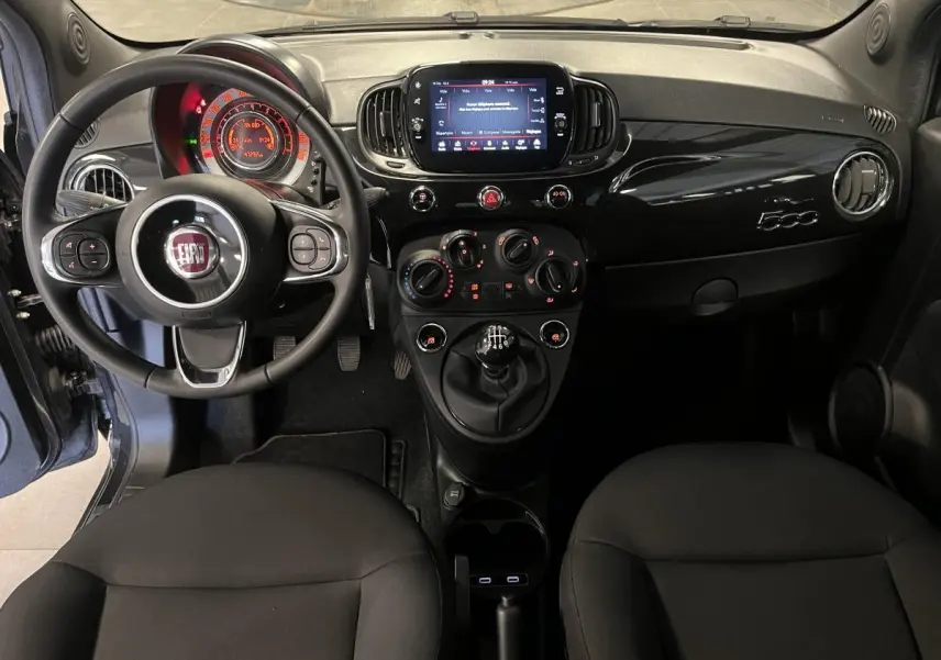 Tableau de bord noir de la Fiat 500 2023 vue de face, avec volant multifonction et écran tactile central.