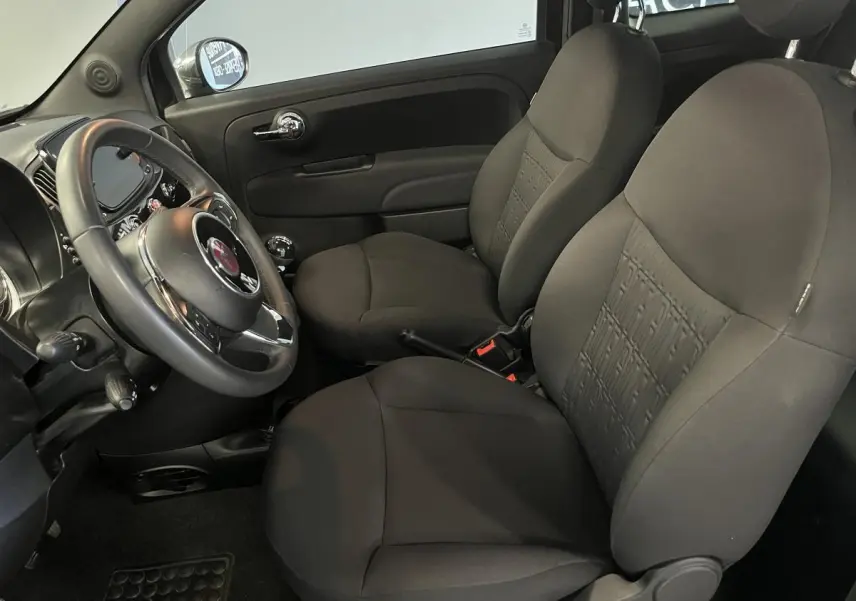 Intérieur avant noir de la Fiat 500 2023, vue côté conducteur avec sièges et volant en tissu sombre.
