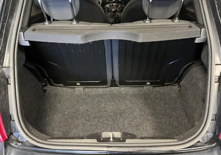 Coffre ouvert vu de l'arrière d'une Fiat 500 noire, montrant la banquette arrière et la surface de chargement.