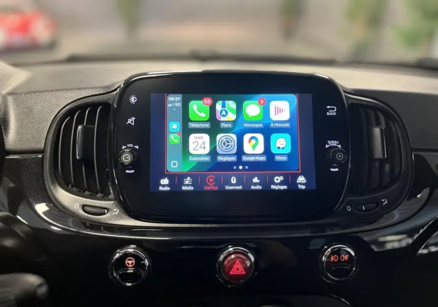 Écran tactile central allumé avec interface Apple CarPlay sur tableau de bord noir brillant d'une Fiat 500 Dolcevita 2023.