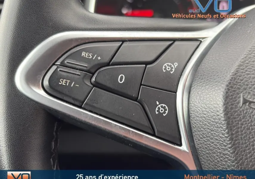 Gros plan sur les commandes du régulateur de vitesse au volant d'une Renault Clio V Blue dCi 85 Business gris foncé.