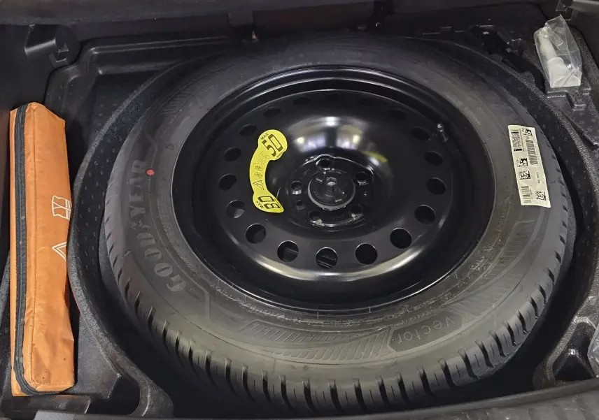 Roue de secours noire Goodyear dans le coffre d'un Jeep Compass 2023, avec trousse à outils orange à gauche.